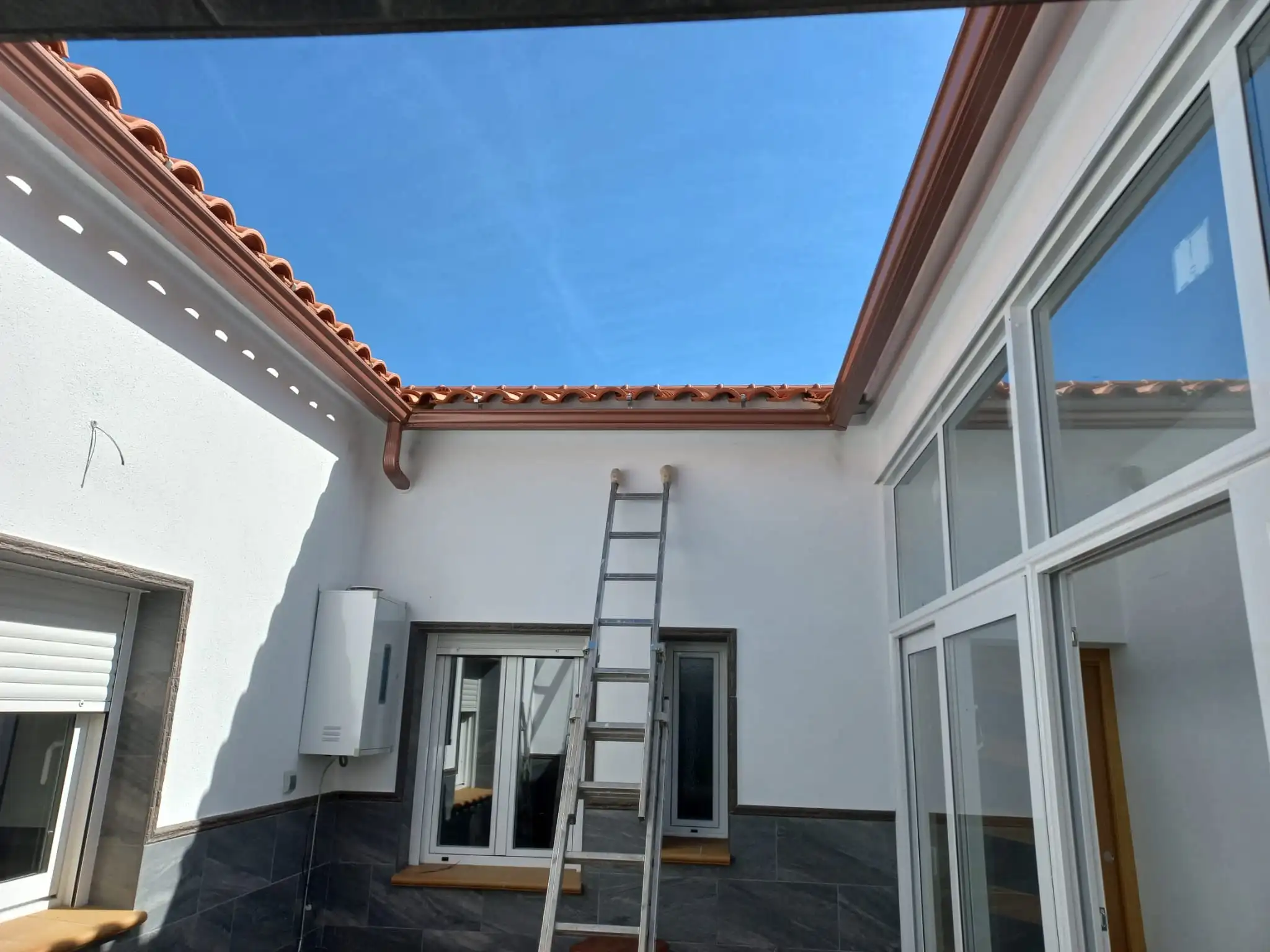 canalon de aluminio en un patio rectangular y el agua entra por un tubo en la pared